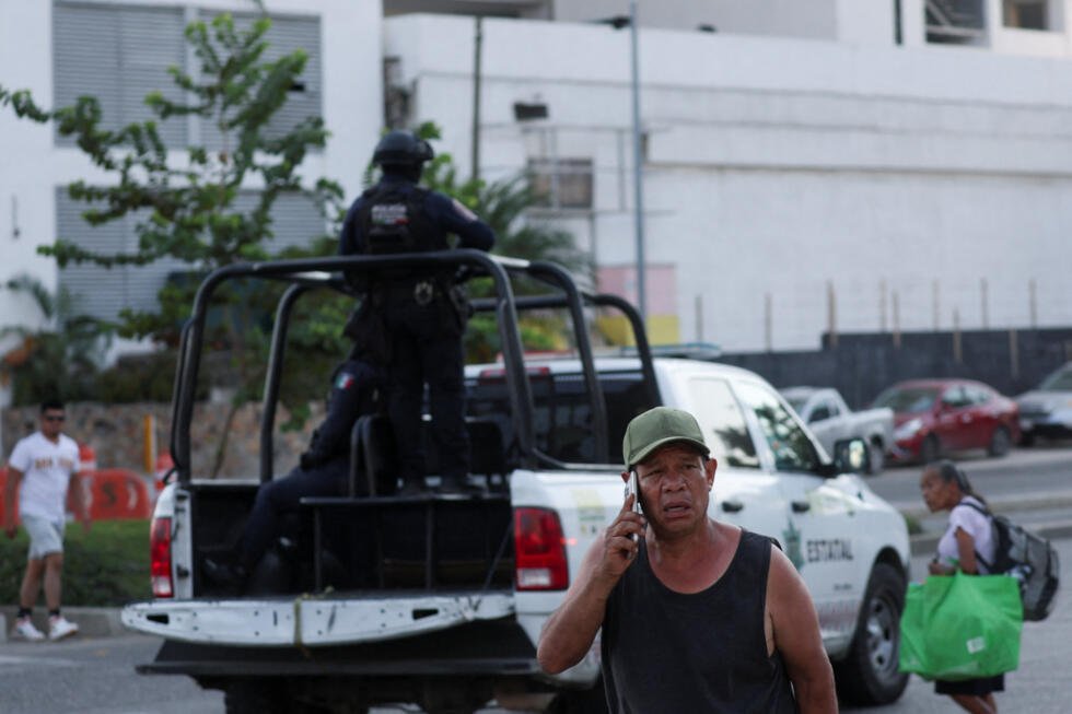 Personas pasan junto a una patrulla policial en la calle, luego de que las autoridades reforzaran la seguridad tras los bloqueos y ataques incendiarios perpetrados por el crimen organizado en varios estados, tras un operativo militar en el que, según una fuente gubernamental, el narcotraficante mexicano Nemesio Oseguera, conocido como "El Mencho", fue asesinado en el estado de Jalisco, en Acapulco, México, el 22 de febrero de 2026.