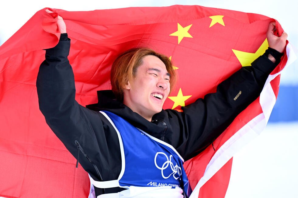 El chino Su Yiming festeja con una bandera de su país su título olímpico en snowboard slopestyle. En Livigno (norte de Italia), el 18 de febrero de 2026