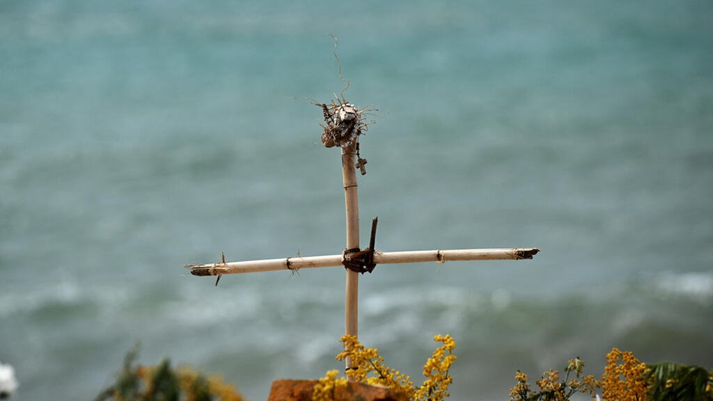 Esta fotografía tomada el 9 de marzo de 2023 muestra una cruz de bambú con un rosario, colocada como monumento conmemorativo en una playa cerca de Cutro, con el mar Mediterráneo de fondo, donde al menos 72 migrantes murieron el 26 de febrero, tras naufragar su embarcación frente a la región de Calabria, en el sur de Italia. El Primer Ministro italiano celebrará una reunión de su gabinete el 9 de marzo cerca del lugar del naufragio mortal, en pleno debate sobre si las políticas migratorias del gobierno de derechas cuestan vidas. (Foto de Tiziana FABI / AFP)