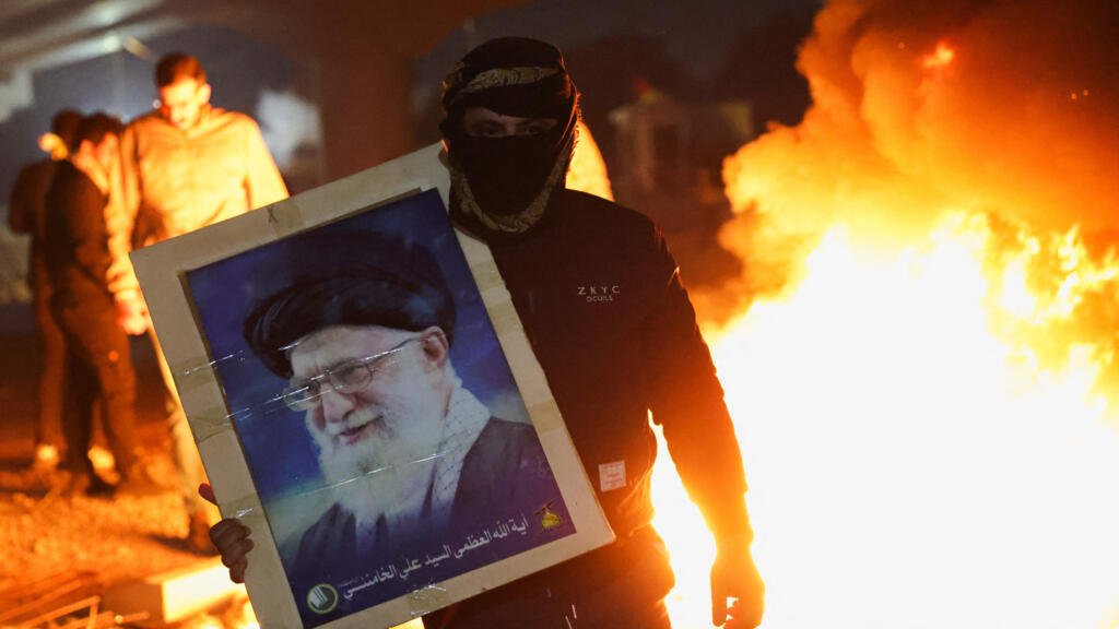 Un manifestante sostiene la imagen del líder supremo de Irán, el ayatolá Ali Jamenei, mientras los partidarios de los grupos armados chiítas de Irak intentan avanzar hacia la embajada estadounidense en Bagdad. 1 de marzo de 2026.