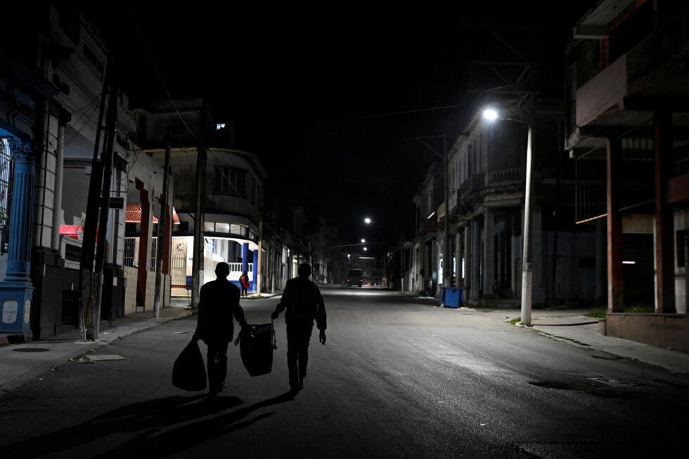 La gente camina cargando bolsas mientras Cuba inicia los esfuerzos para restablecer el suministro eléctrico tras el colapso de la red eléctrica por segunda vez en una semana, en medio de un bloqueo petrolero de Estados Unidos que ha asestado un duro golpe a la ya deteriorada infraestructura energética de la isla, en La Habana, Cuba, el 22 de marzo de 2026.