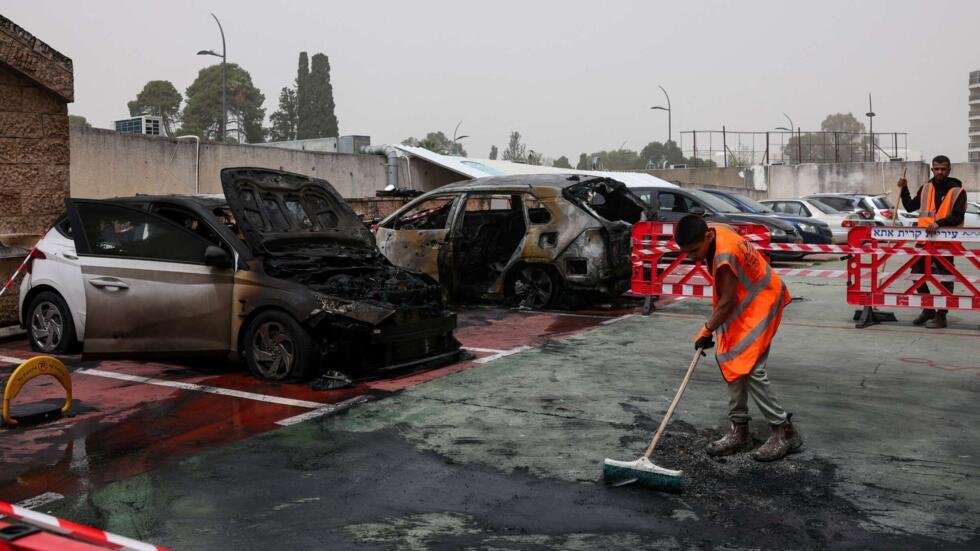 Miembros de un equipo de limpieza trabajan junto a vehículos destruidos en el lugar del impacto de un proyectil lanzado por Irán, en Kiryat Ata, al norte de Israel, el 3 de abril de 2026.